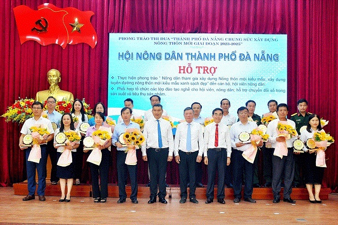 Da Nang People's Committee Vice Chairman Ho Ky Minh (fiftth, left) and Head of the Municipal Party Committee's Mass Mobilization Commission Le Van Trung (fifth, right) present flowers and honor the units that have registered to support Hoa Vang to build new rural areas for the 2023-2025 period. Photo: H.VANG