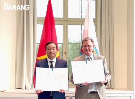 Chủ tịch UBND thành phố Lê Trung Chinh (bên trái) và Thủ hiến bang Thuringen Bolo Ramelow trao đổi văn bản ghi nhớ hữu nghị và hợp tác. Ảnh: ĐOÀN CÔNG TÁC