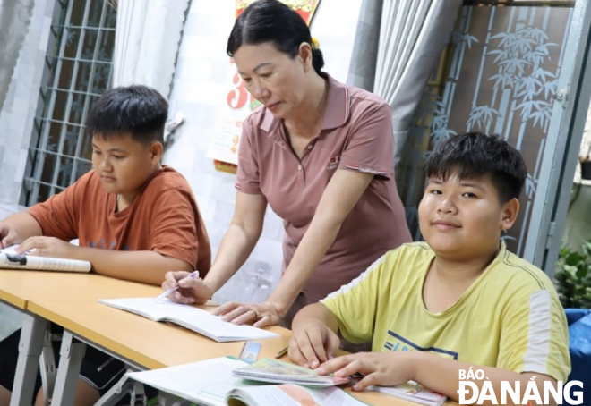 Cô Đào Thị Nhung đang kiểm tra bài, hướng dẫn trẻ em có hoàn cảnh khó khăn hiếu học tại “Lớp hoc hạnh phúc” do cô mở 