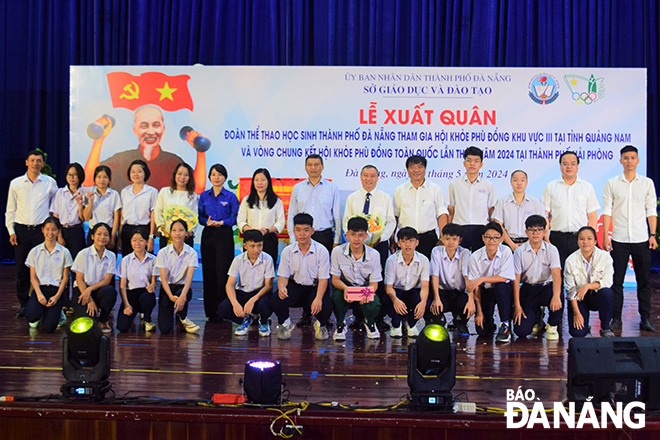 Phó Chủ tịch Thường trực UBND thành phố Hồ Kỳ Minh (thứ 8, bên trái sang) tặng hoa chúc mừng đoàn thể thao học sinh thành phố tại lễ xuất quân. 