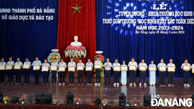 Phó Chủ tịch UBND thành phố Lê Quang Nam (giữa) tặng thưởng cho các học sinh tiêu biểu. Ảnh: NGỌC HÀ