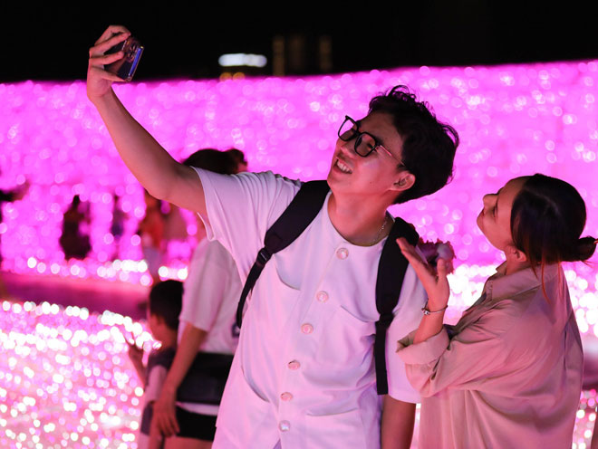 Young people enjoy taking beautiful photos at an artistic light space held on the sidewalk area along the western bank of the Han River in celebration for the 50th anniversary of the diplomatic relationship between Viet Nam and Japan. Photo: ST