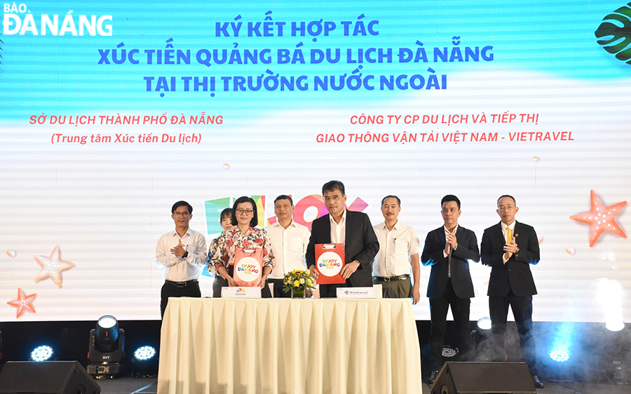 Standing Vice Chairman of the Da Nang People's Committee Ho Ky Minh (5th, right) witnessing the cooperation signing between representatives of the Department of Tourism and businesses. Photo: THU HA