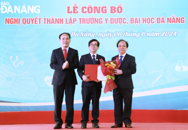 Assoc. Prof. Dr. Nguyen Ngoc Vu, Director of the University of Da Nang (right), and Dr. Phan Minh Duc, Chairman of the Council of the University of Da Nang (left), giving the resolution of the Council of the University of Da Nang to establish the School of Medicine and Pharmacy to the school leader. Photo: NGOC HA