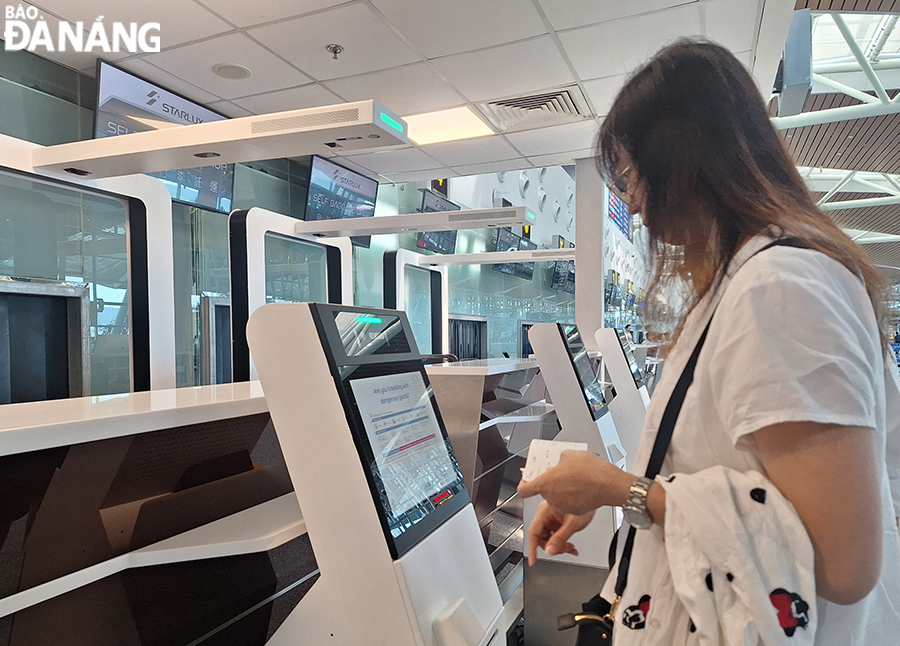 The operation of self-service bag drop kiosks at Da Nang Airport's International Terminal T2 helps passengers shorten check-in time. In the photo: A tourist checking in her checked baggage at the airport herself. Photo: THU HA