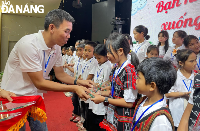 Mr. Nguyen Binh Nam giving medals to pupils with outstanding academic achievements.