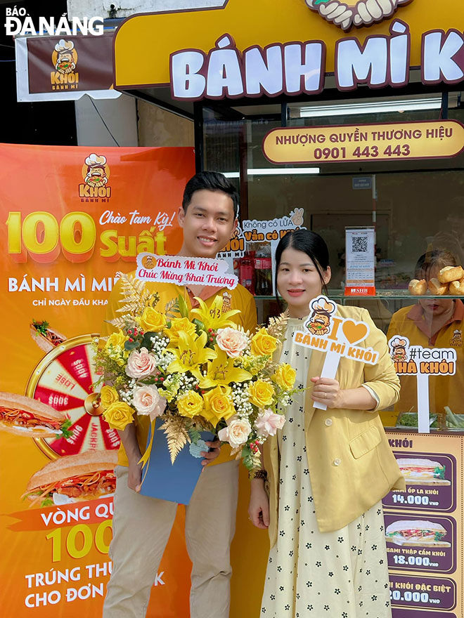 Le Duc Nguyen (left) presents flowers to congratulate a ‘Khoi’ facility in Tam Ky City that does business in the form of franchise. Photo: K.N