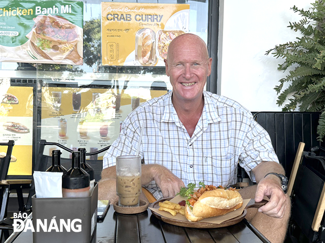 A tourist from The Netherlands enjoys ‘banh mi’ at a shop on Bach Dang Street, Da Nang Photo: Y.D