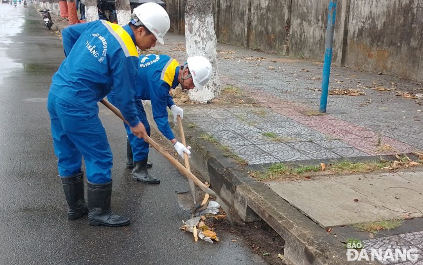 Công nhân Công ty Thoát nước và xử lý nước thải Đà Nẵng tranh thủ khơi thông cửa thu nước mưa trên đường Trường Chinh. Ảnh: H.H