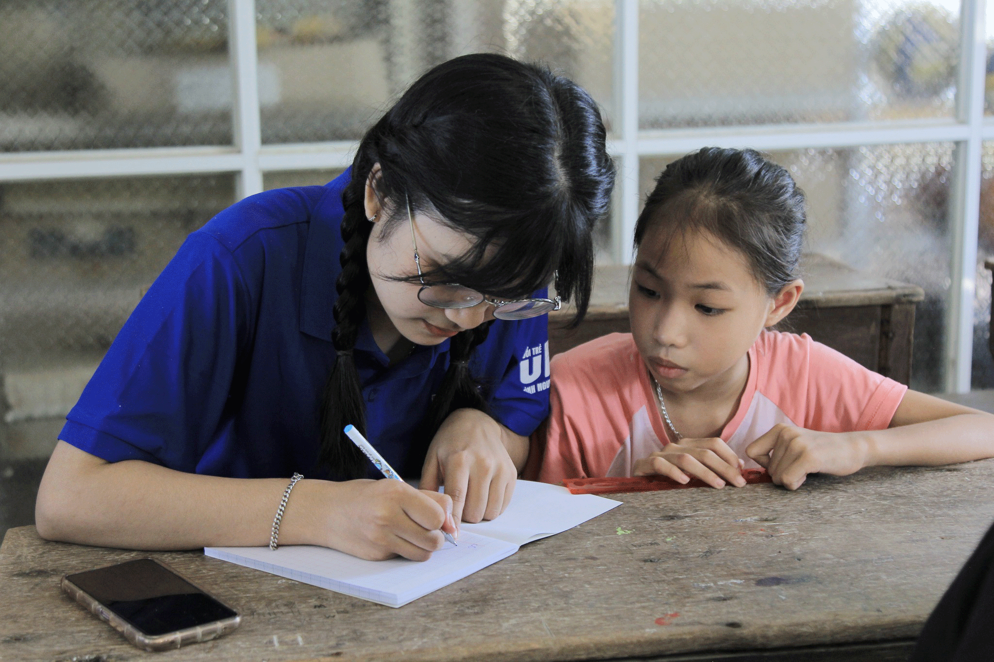 A volunteer guiding a child to write letters beatifully during the 2024 “Green Summer” campaign launched by the University of Science and Education under the University of Da Nang in Dien Phong Commune, Quang Nam Province.