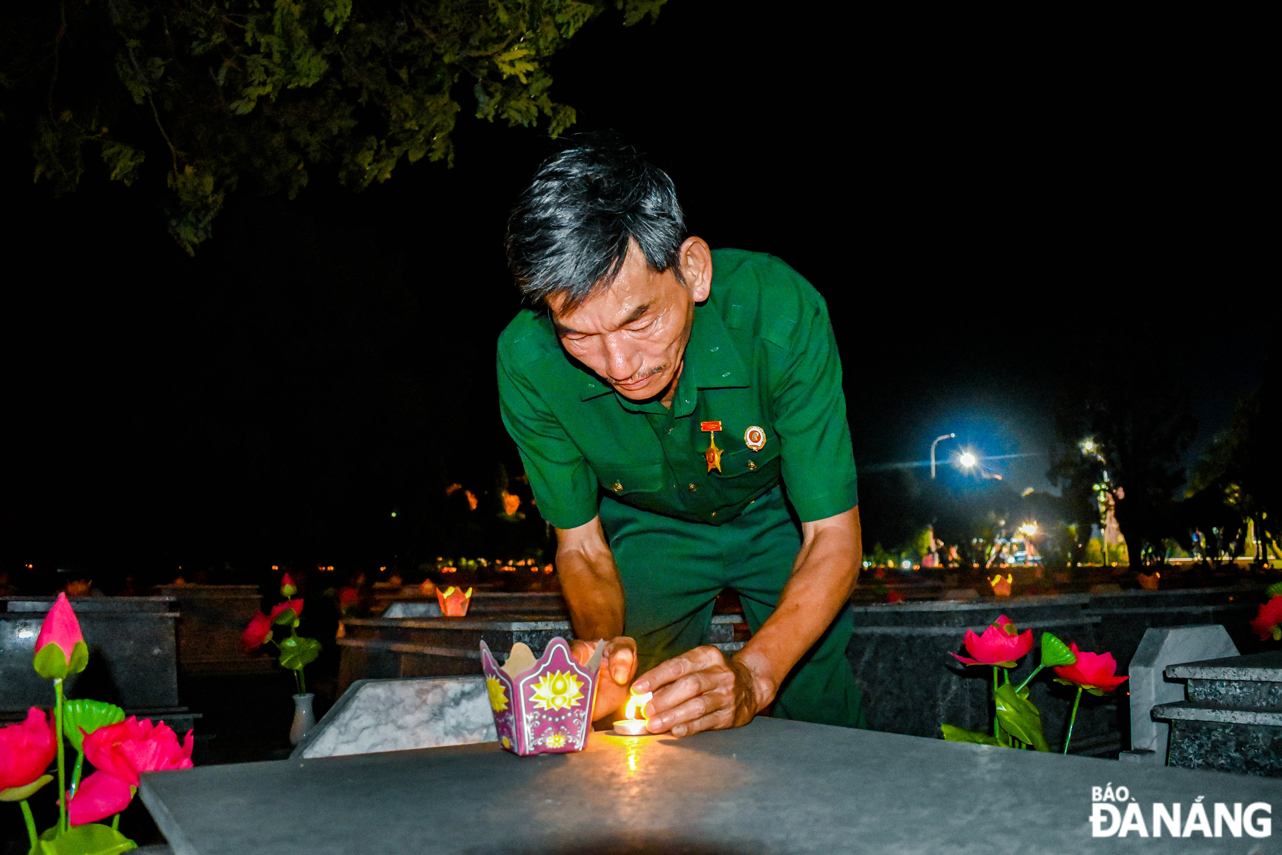 A war veteran lighting flower lanterns in memory of his fallen comrades at the city's martyrs cemetery in Hoa Khuong Commune, Hoa Vang District.