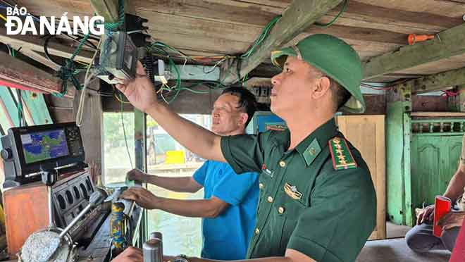 Cán bộ biên phòng kiểm tra tình trạng hoạt động của thiết bị giám sát hành trình trên tàu cá ngư dân. Ảnh: KIM NGÂN	