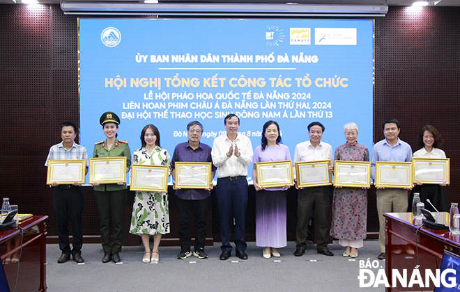 Chairman of the Da Nang People's Committee Le Trung Chinh (5th, left) giving Certificates of Merit to groups and individuals involved in organising DANAFF II. Photo: X.D