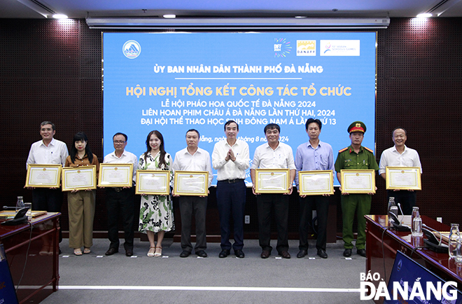 Chairman of the Da Nang People's Committee Le Trung Chinh (5th, right) giving Certificates of Merit to groups and individuals involved in organising ASG. Photo: X.D