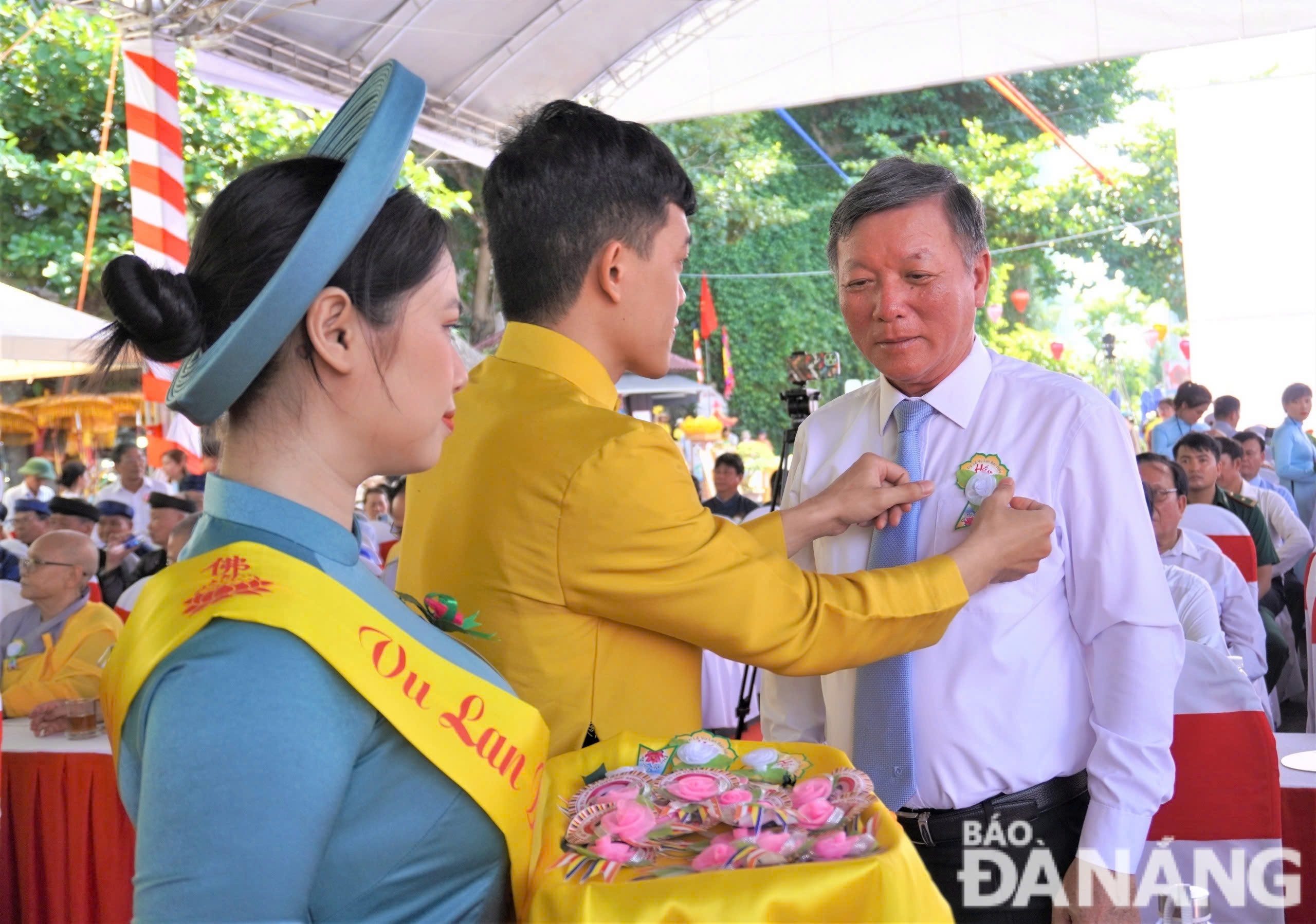 Chủ tịch Ủy ban MTTQ Việt Nam thành phố Lê Văn Trung (bên phải) được cài hoa hồng hiếu hạnh. Ảnh: N.QUANG