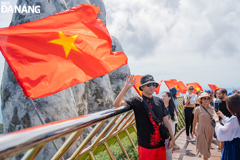 Sun World Ba Na Hills tourist area is brightly decorated with national flags. In the photo: International tourists enjoy checking in at the Golden Bridge. Photo: THU HA.