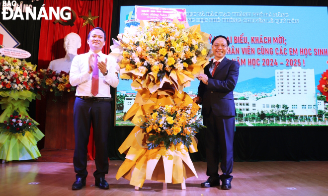 Phó Bí thư Thường trực Thành ủy Nguyễn Đình Vĩnh (bên trái) tặng hoa chúc mừng thầy và trò Trường THPT chuyên Lê Quý Đôn. Ảnh: NGỌC HÀ   