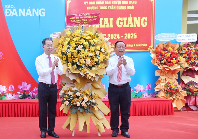 Bí thư Thành ủy, Trưởng đoàn đại biểu Quốc hội thành phố Nguyễn Văn Quảng (bên trái) tặng hoa chúc mừng thầy và trò nhà trường. Ảnh: LAM PHƯƠNG