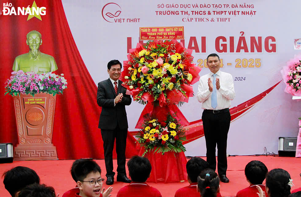 Standing Vice Chairman of the municipal People's Committee Ho Ky Minh (right) sending flowers to congratulate teachers and pupils of the Viet Nhat Primary, Secondary and High School. Photo: X.D