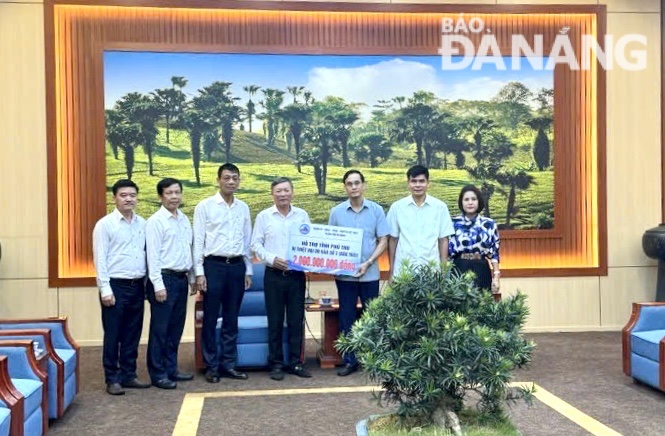 Chairman of the Viet Nam Fatherland Front Committee of Da Nang Le Van Trung (middle) giving a symbolic board of donations worth VND 2 billion to to Phu Tho Province. Photo: M.T