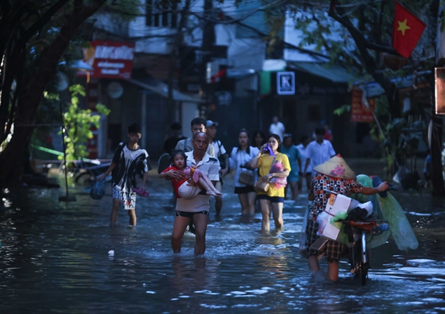 People evacuate from their houses on Cau Dat Street, Hoan Kiem District as rising water level in the Red River flooded the area. Source: VNA/VNS Photos