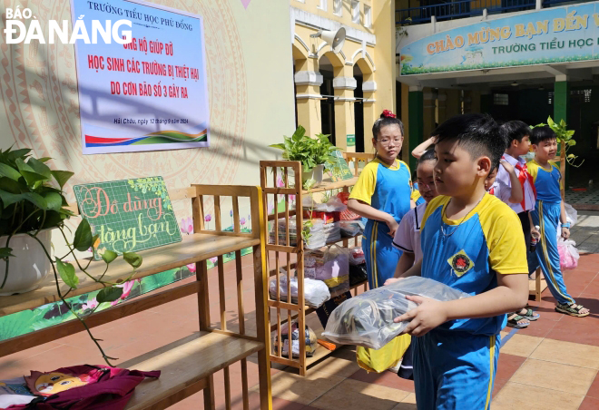 Tại Trường Tiểu học Phù Đổng (quận Hải Châu), nhà trường kêu gọi học sinh tặng bạn đồ dùng học tập, sách vở, áo quần… Khá nhiều học sinh tự tay mang những đồ dùng này xếp gọn gàng vào kệ thu gom để giáo viên nhà trường dễ dàng phân loại và gửi đi. Ảnh: NGỌC HÀ