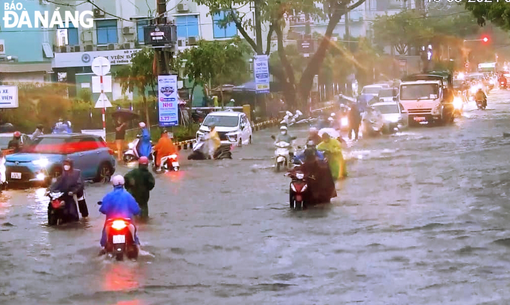 Mưa lớn khiến đường Quang Trung nước ngập sâu, gậy khó khăn cho phụ huynh, học sinh Trường THCS Nguyễn Huệ đưa đón con đến trường. Ảnh: NGỌC HÀ