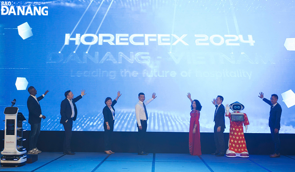 Standing Vice Chairman of the Da Nang People's Committee Ho Ky Minh (middle) and delegates making a symbolic gesture to open the event. Photo: THU HA