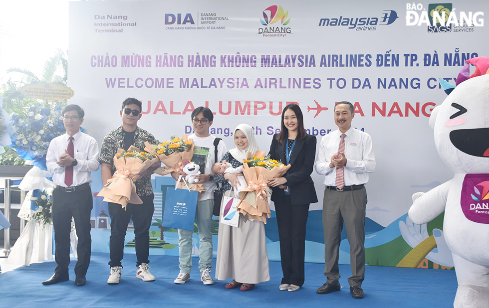 The three luckiest passengers of the flight receiving flowers and special gifts from Malaysia Airlines and Da Nang's tourism authorities