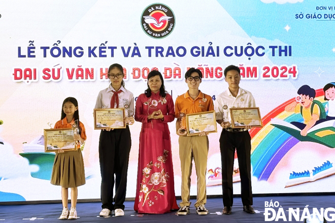 Mrs. Mai Thi Thu, Deputy Head of Da Nang Party Committee's Publicity and Training Department, giving cups and certificates to outstanding students who won the 