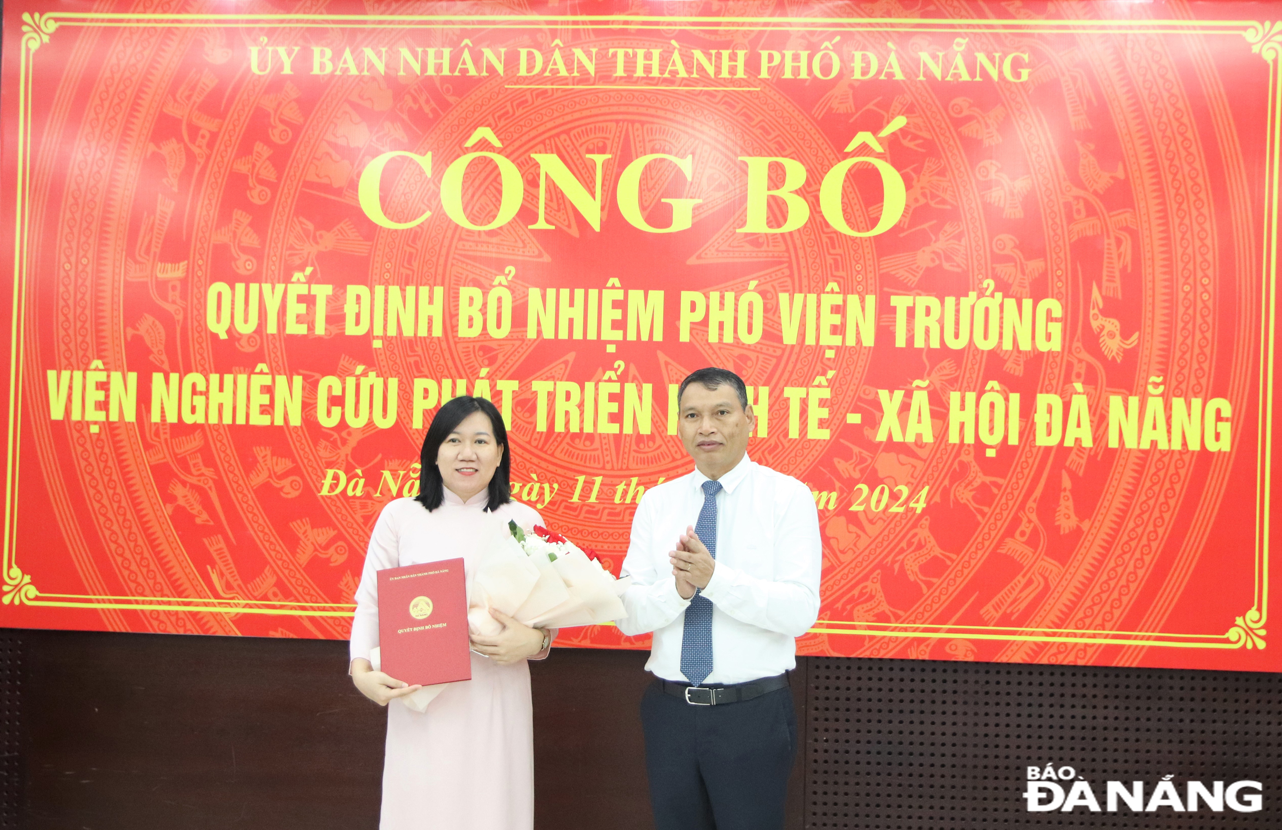 Phó Chủ tịch Thường trực UBND thành phố Hồ Kỳ Minh trao quyết định, tặng hoa chúc mừng bà Nguyệt. Ảnh: T. HUY