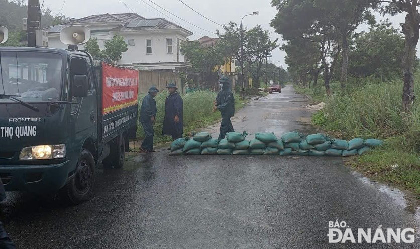 Lực lượng chức năng đắp các bao cát để ngăn nước chảy gây xói lở. Ảnh: H.H