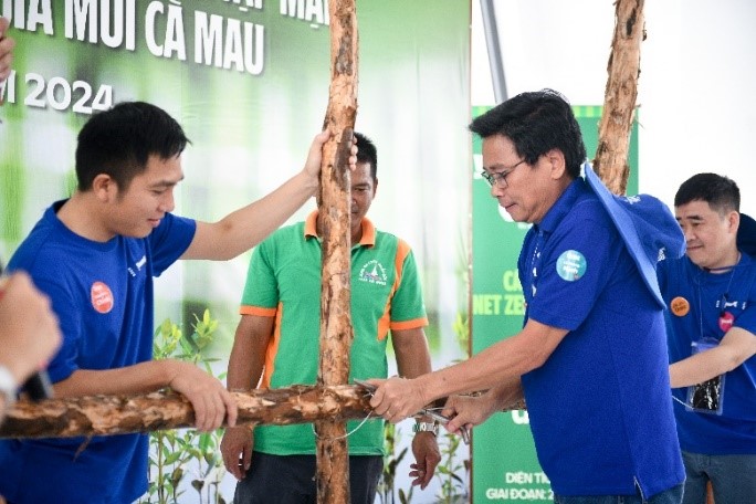 Ông Lê Hoàng Minh thực hiện mẫu thao tác buộc thép các cọc cừ tràm để làm hàng rào khoanh nuôi. Ảnh: Công ty VNM cung cấp