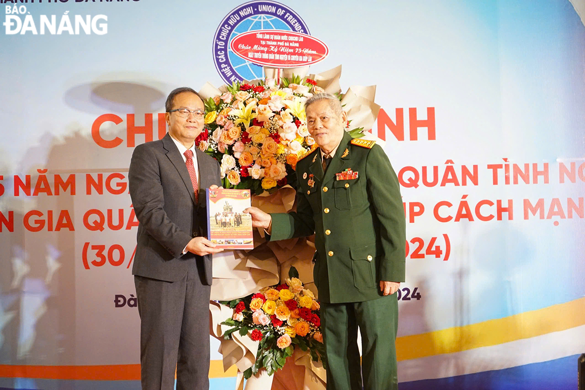 Colonel Tran Nhu Tiep, Head of the Liaison Committee of Vietnamese Volunteer Soldiers and Military Experts to Help the Lao Revolution in Da Nang (right) giving a yearbook to Lao Consul General in the city Souphanh Hadaoheuang. Photo: T.P