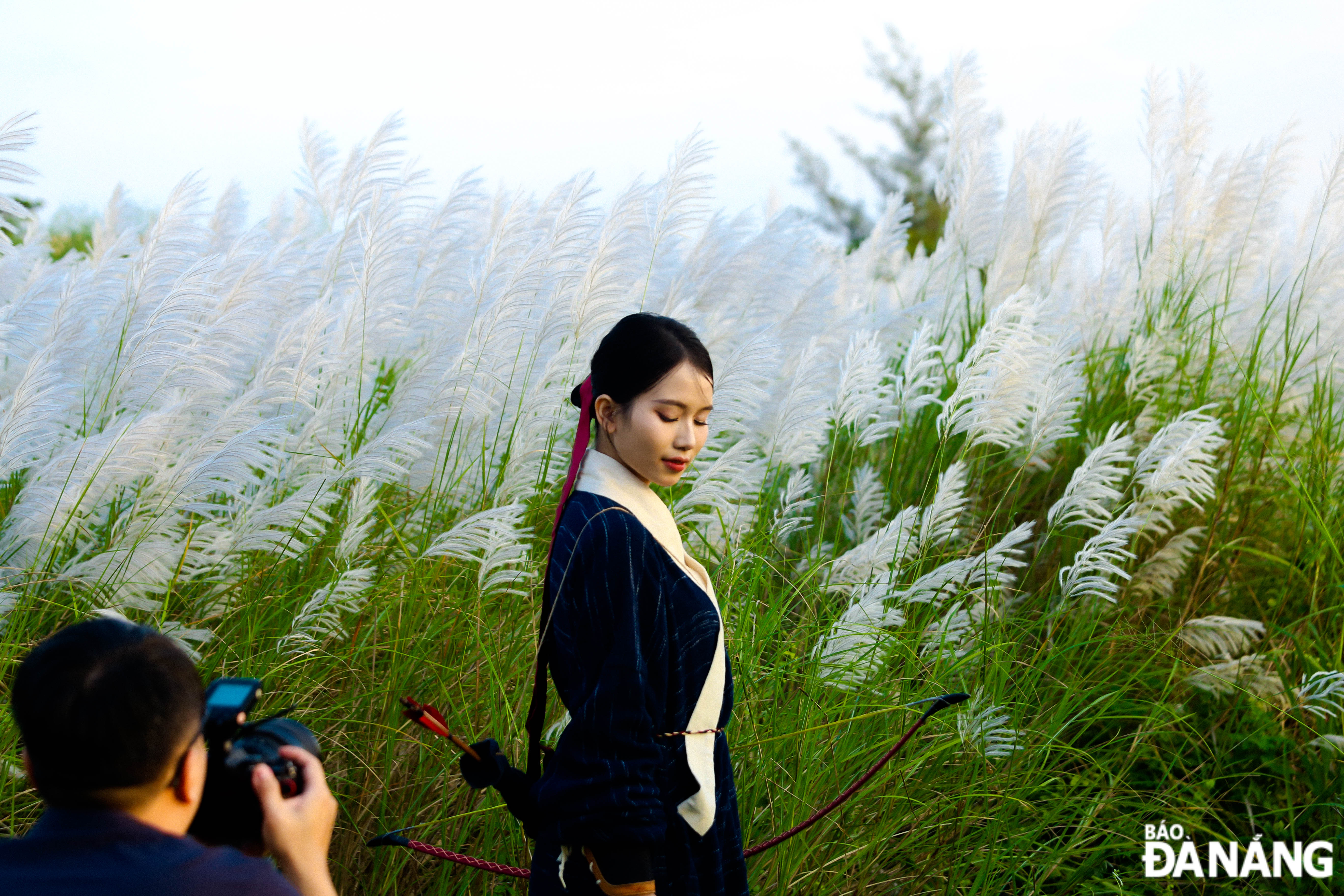 A woman poses for pictures at a white reed field 