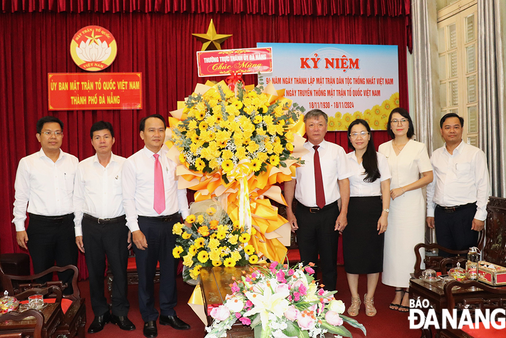 Standing Deputy Secretary of the municipal Party Committee Nguyen Dinh Vinh (third from left) presents flowers to congratulate the Viet Nam Fatherland Front Committee of the city on special day. Photo: DAC MANH