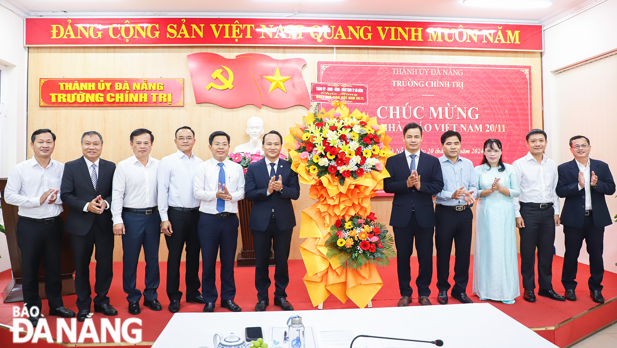 Phó Bí thư Thường trực Thành ủy Nguyễn Đình Vĩnh (thứ 6, trái sang) tặng hoa chúc mừng Trường Chính trị thành phố nhân kỷ niệm 42 năm ngày Nhà giáo Việt Nam. Ảnh: NGỌC PHÚ