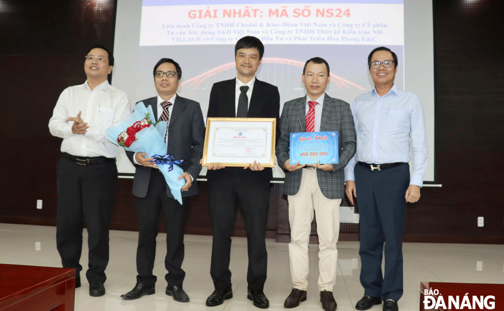 Mr Vu Quang Hung (right), Head of the Da Nang High-Tech Park and Industrial Zones Authority, and Mr Nguyen Minh Huy (left), Director of the Management Board of Da Nang Traffic Construction Investment Projects, present the first prize to the winning team. Photo: TRONG HUNG