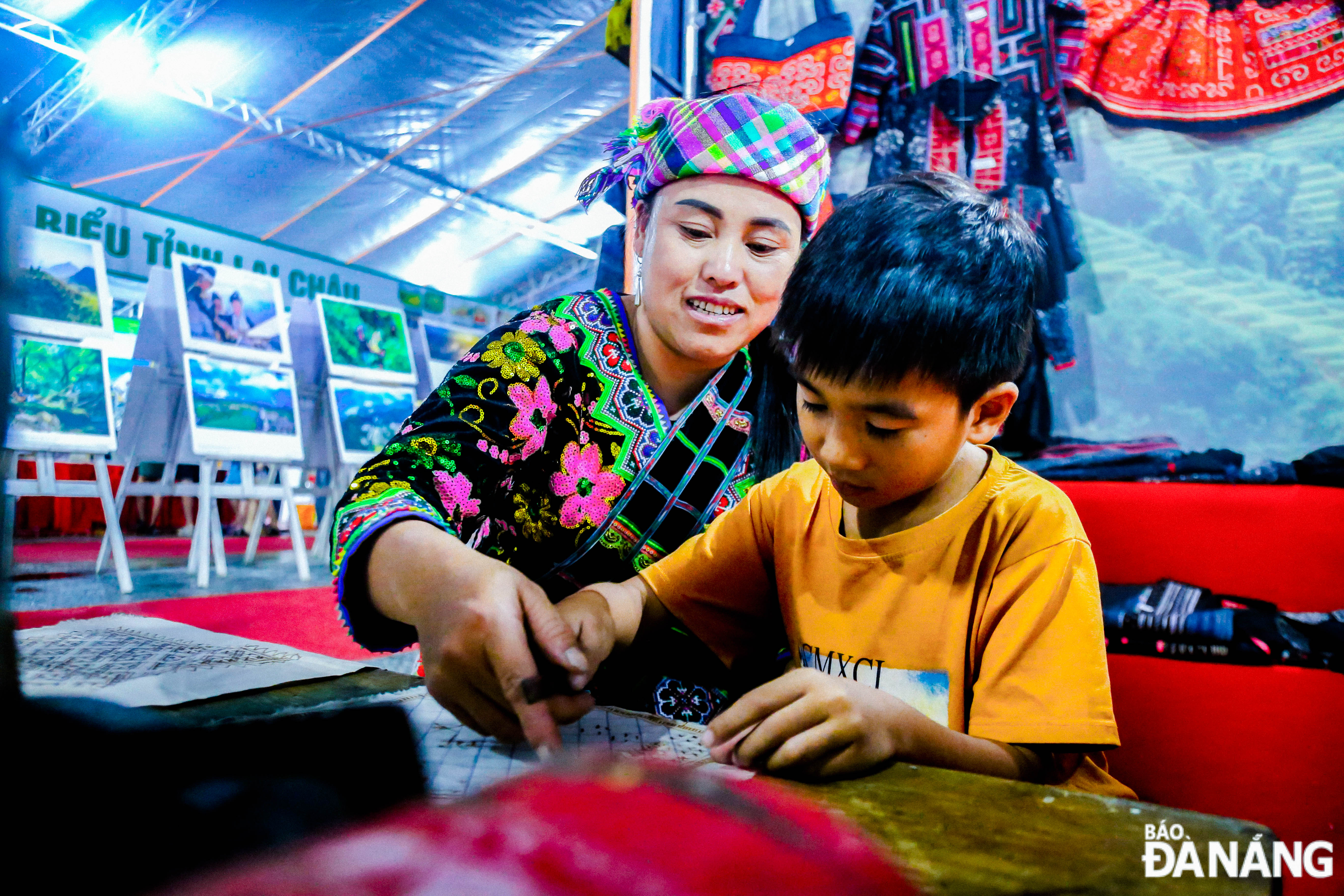 A woman from Lai Chau Province is seen guiding tourists the technique of creating patterns on fabric with beeswax.