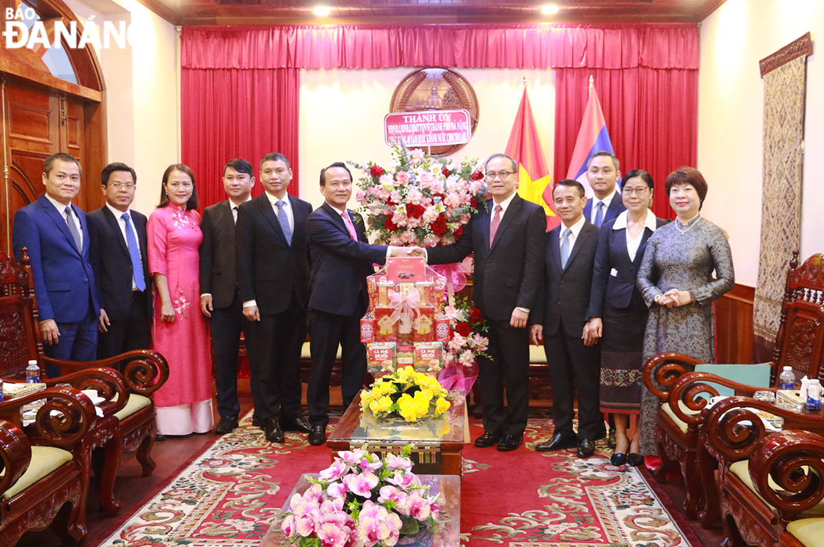 Phó Bí thư Thường trực Thành ủy Nguyễn Đình Vĩnh (thứ , trái sang) tặng hoa chúc mừng Tổng Lãnh sự Lào tại Đà Nẵng Souphanh Hadaoheuang và toàn thể cán bộ, nhân viên Tổng Lãnh sự. Ảnh: T.PHƯƠNG