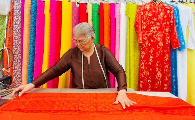 At the age of 85, Mrs. Van Ha, the wife of artisan Van Ha, still passionately devotes herself to tailoring and cherishes her deep love for the ao dai. Photo: T.V.