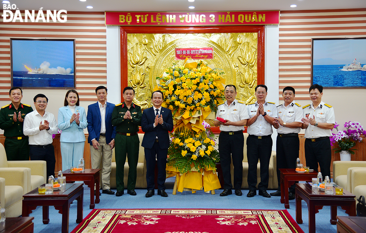 Phó Bí thư Thường trực Thành ủy Nguyễn Đình Vĩnh (thứ 6, bên trái) tặng hoa và quà chúc mừng Bộ Tư lệnh Vùng 3 Hải quân. Ảnh: XUÂN DŨNG