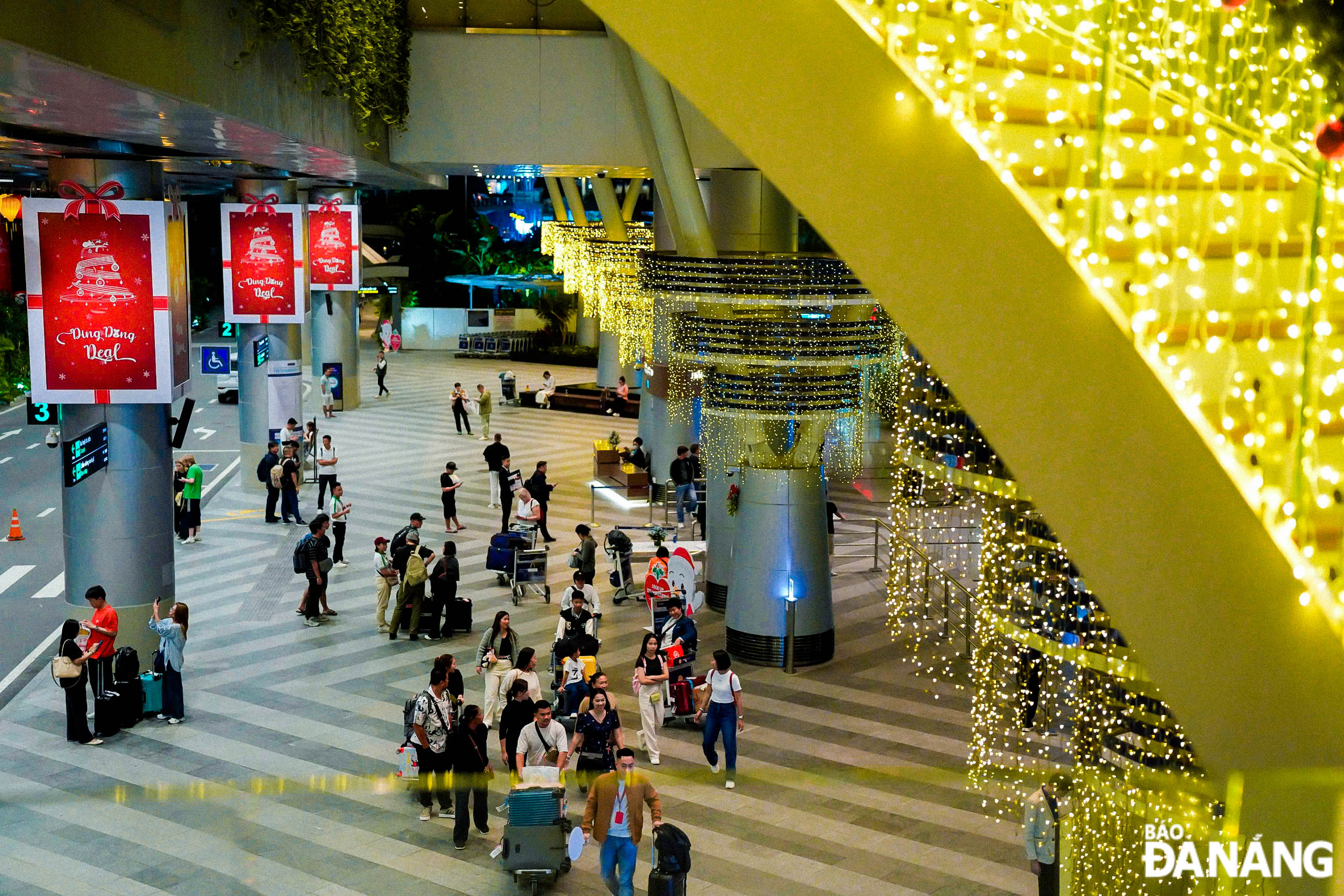 International tourists walk under the bright, warm space before Christmas season