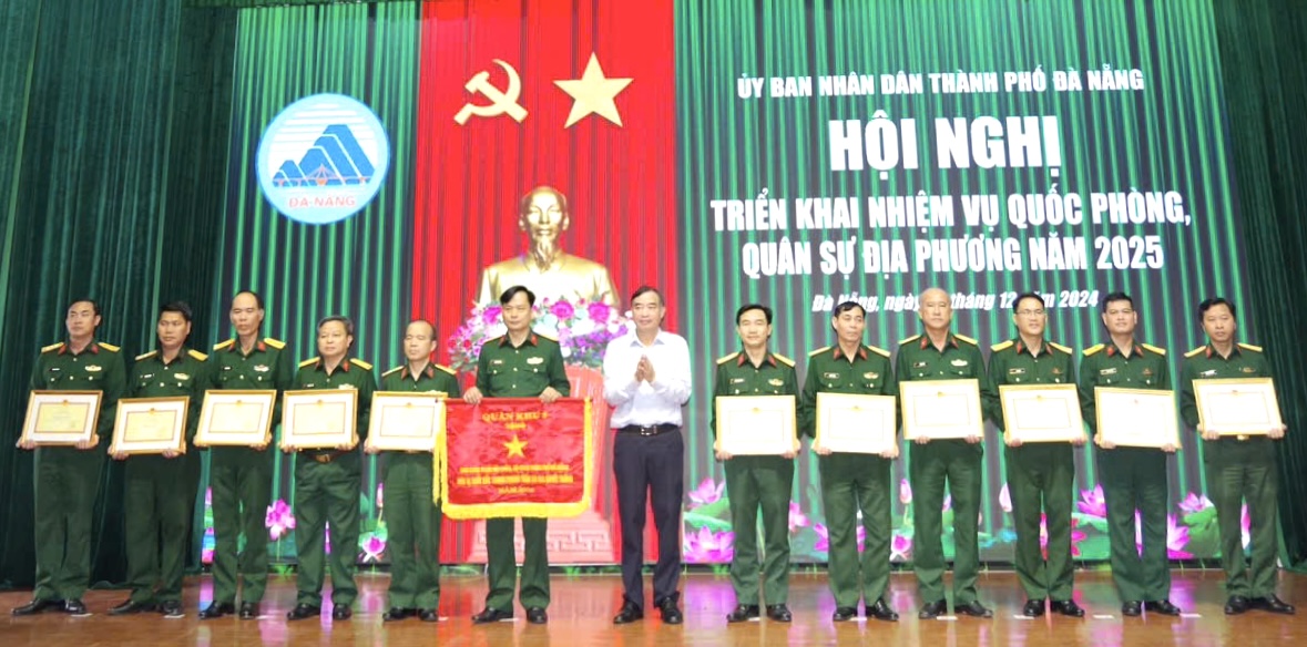 Thượng tá Trương Kim Hòa (thứ 6, bên trái sang), Chỉ huy trưởng Ban Chỉ huy Quân sự quận Hải Châu nhận Cờ thi đua xuất sắc của Bộ Tư lệnh Quân khu 5 về thành tích trong phong trào thi đua Quyết thắng - đơn vị dẫn đầu trong lực lượng vũ trang năm 2024. Ảnh: DIỆP NHƯ	