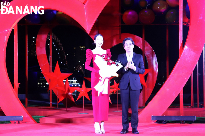 Vice Chairman of the Da Nang People's Committee Tran Chi Cuong (right) presented flowers to Miss Huynh Thi Thanh Thuy for accompanying the city's event.