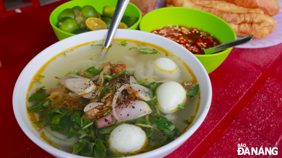 For late afternoons, when hunger strikes, Nam O noodle is a perfect choice on a cold day. Photo: A bowl of Nam O noodle topped with stewed mackerel, quail eggs, and pork sausage, priced at VND 15,000.  This dish is served at Thang's eatery, which has been operating for 26 years on Ngo Xuan Thu Street, Hoa Hiep Bac Ward, Lien Chieu District.