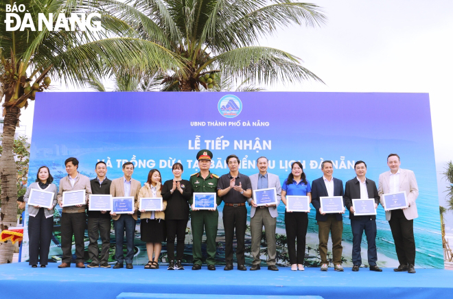 Vice Chairman of the Da Nang People's Committee, Tran Chi Cuong (right, sixth), presenting symbols of appreciation to units contributing coconut trees. Photo: NGOC HA