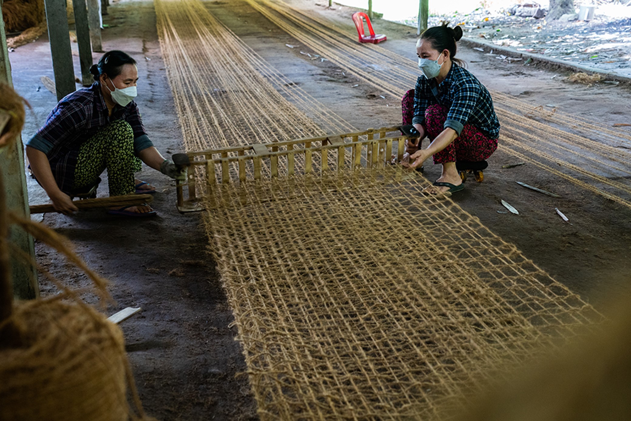 Coconut coir mats are woven in two layers, each measuring 10 meters in length. Two artisans work together on a single weaving frame.