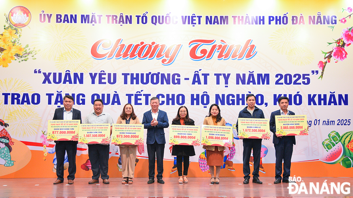 Chủ tịch Ủy ban MTTQ Việt Nam thành phố Lê Văn Trung (thứ) trao bảng tượng trưng số lượng hỗ trợ quà Tết các hộ nghèo cho Mặt trận 7 quận, huyện. Ảnh: T.PHƯƠNG