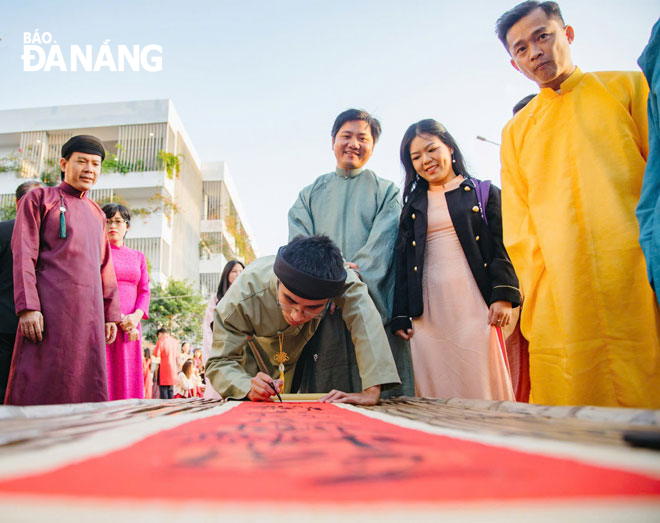 Người dân thích thú xem Lê Đình Nhật viết thư pháp.  Ảnh: XUÂN HẬU